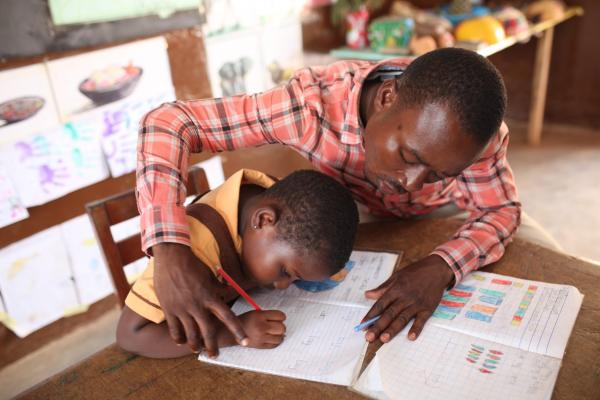 A teacher helps a pupil with special need to write. A UNICEF photo.