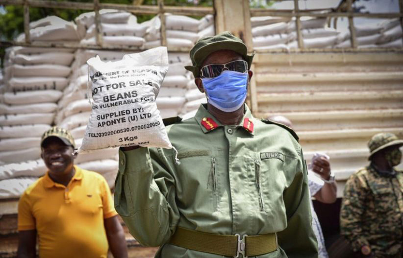 Former Security Minister Gen Elly Tumwine holds a bad of Covid 19 relief posho last year. Courtesy photo.